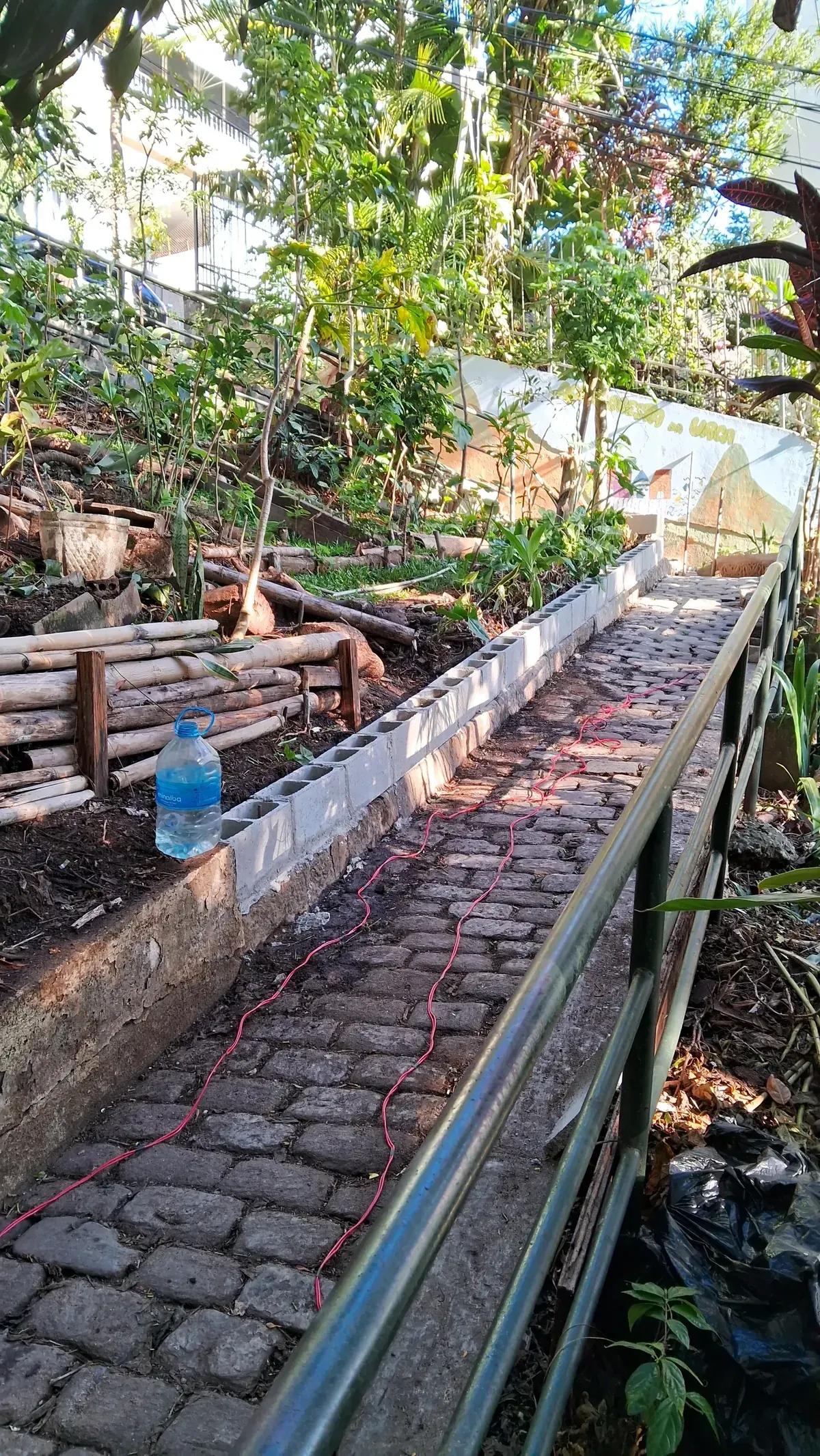 Escadaria de pedra durante a obra, com canteiro de madeira à esquerda e mangueira estendida no chão